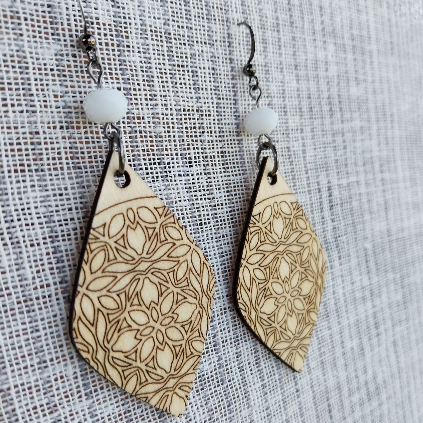 Boucles d'oreille dentelle de bois gravé et perles à facettes blanc laiteux.
