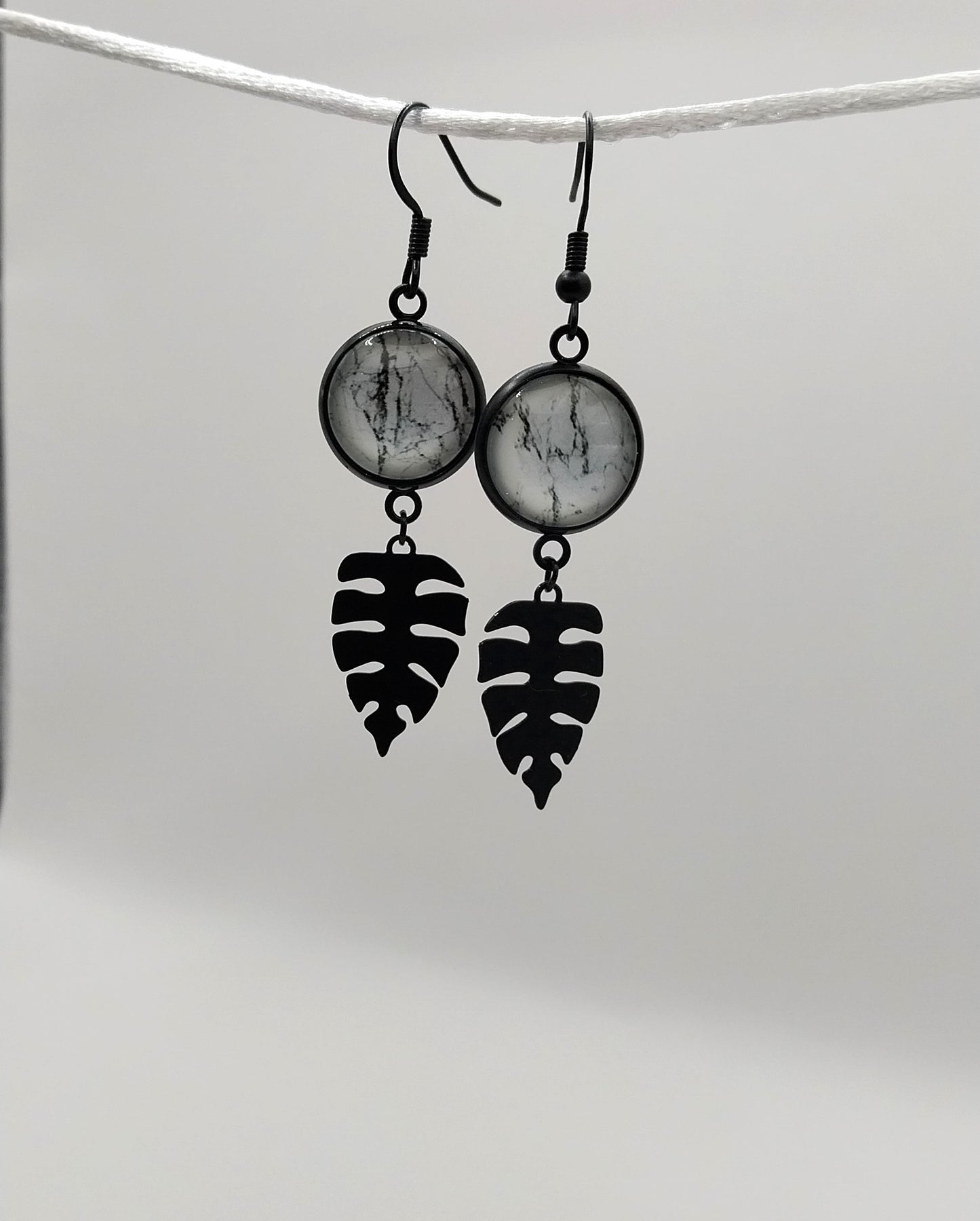 Boucles d'oreille cabochon marbré noir et blanc et breloque feuille tropicale