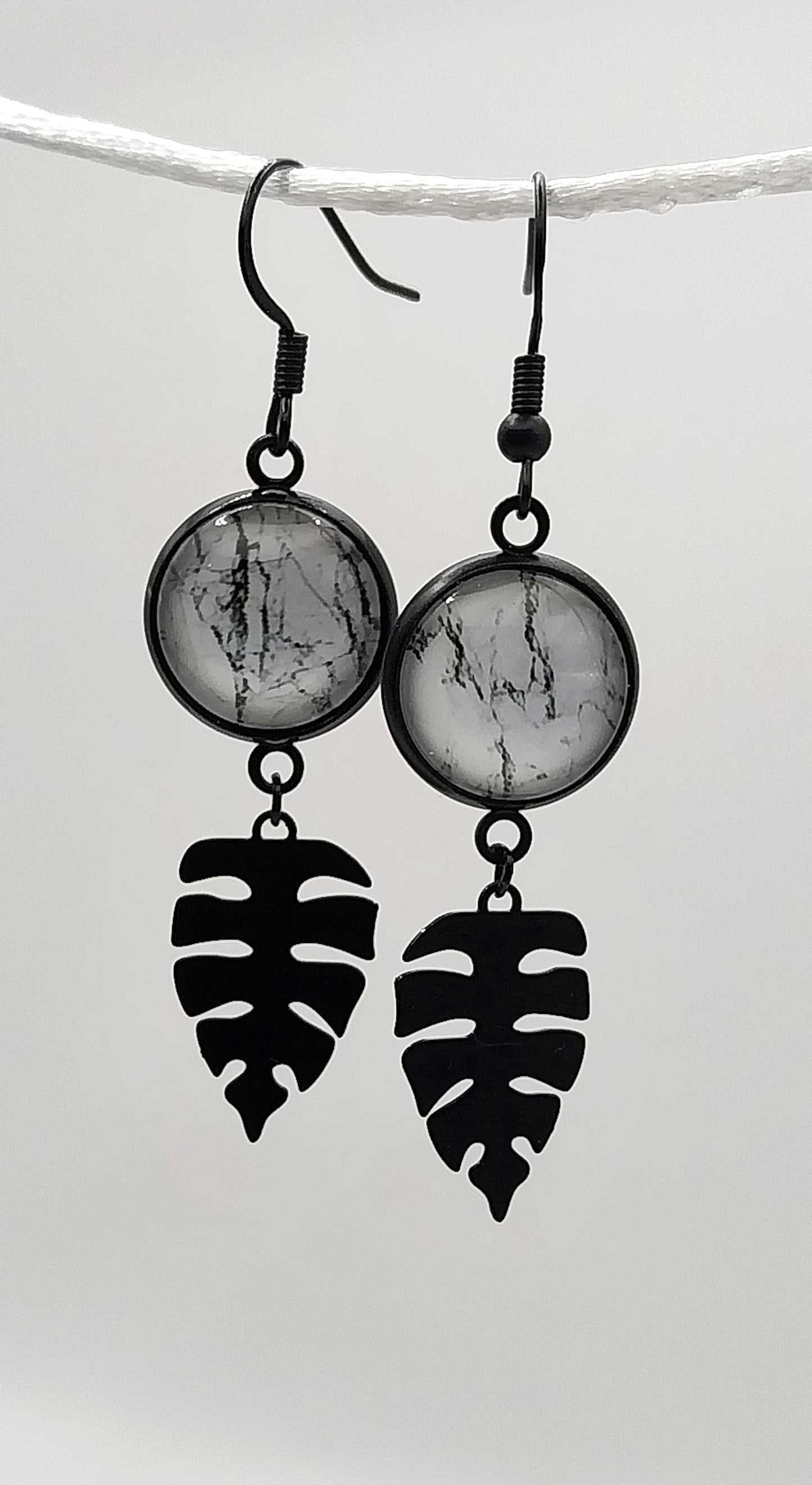 Boucles d'oreille cabochon marbré noir et blanc et breloque feuille tropicale