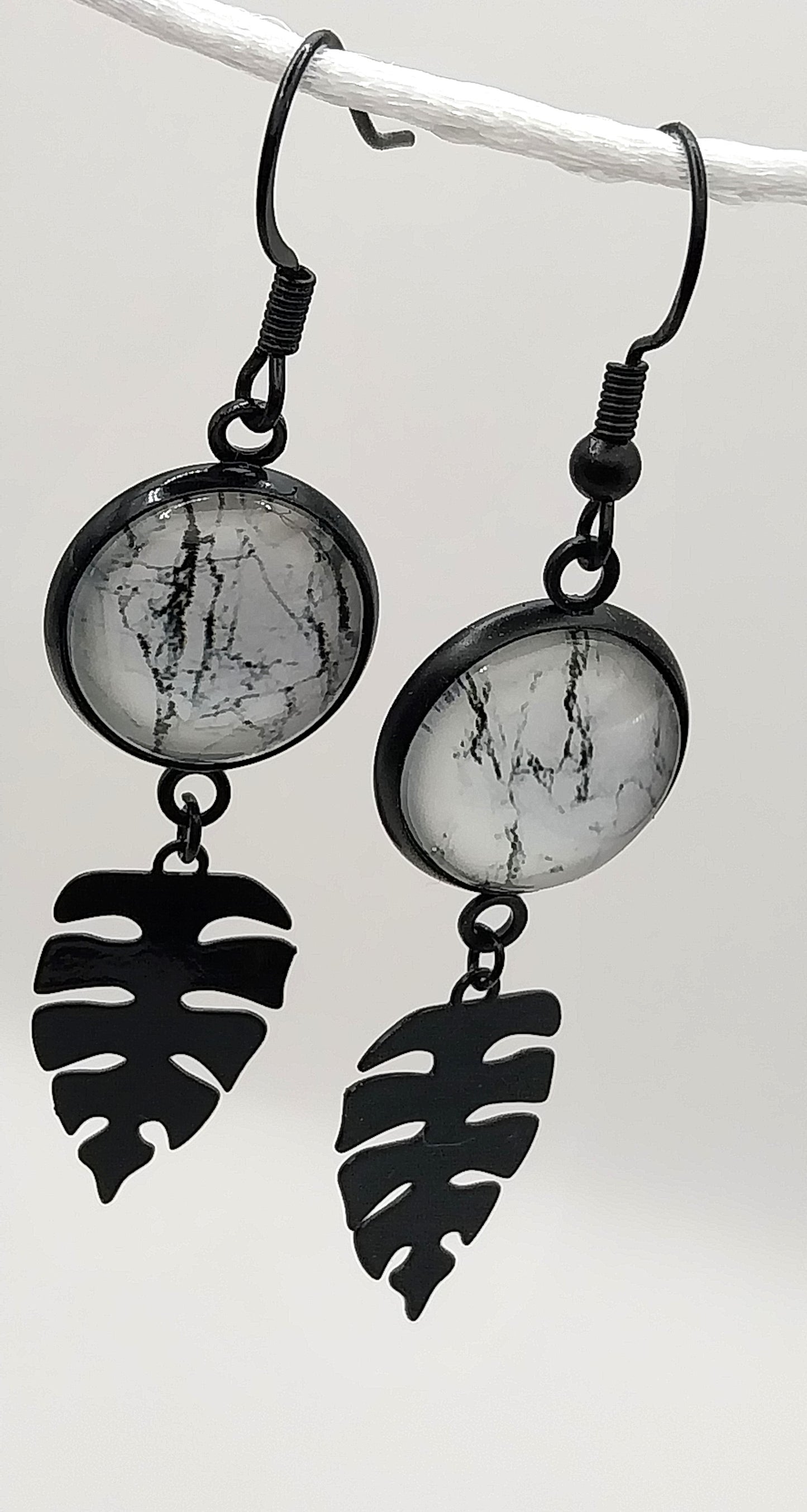 Boucles d'oreille cabochon marbré noir et blanc et breloque feuille tropicale