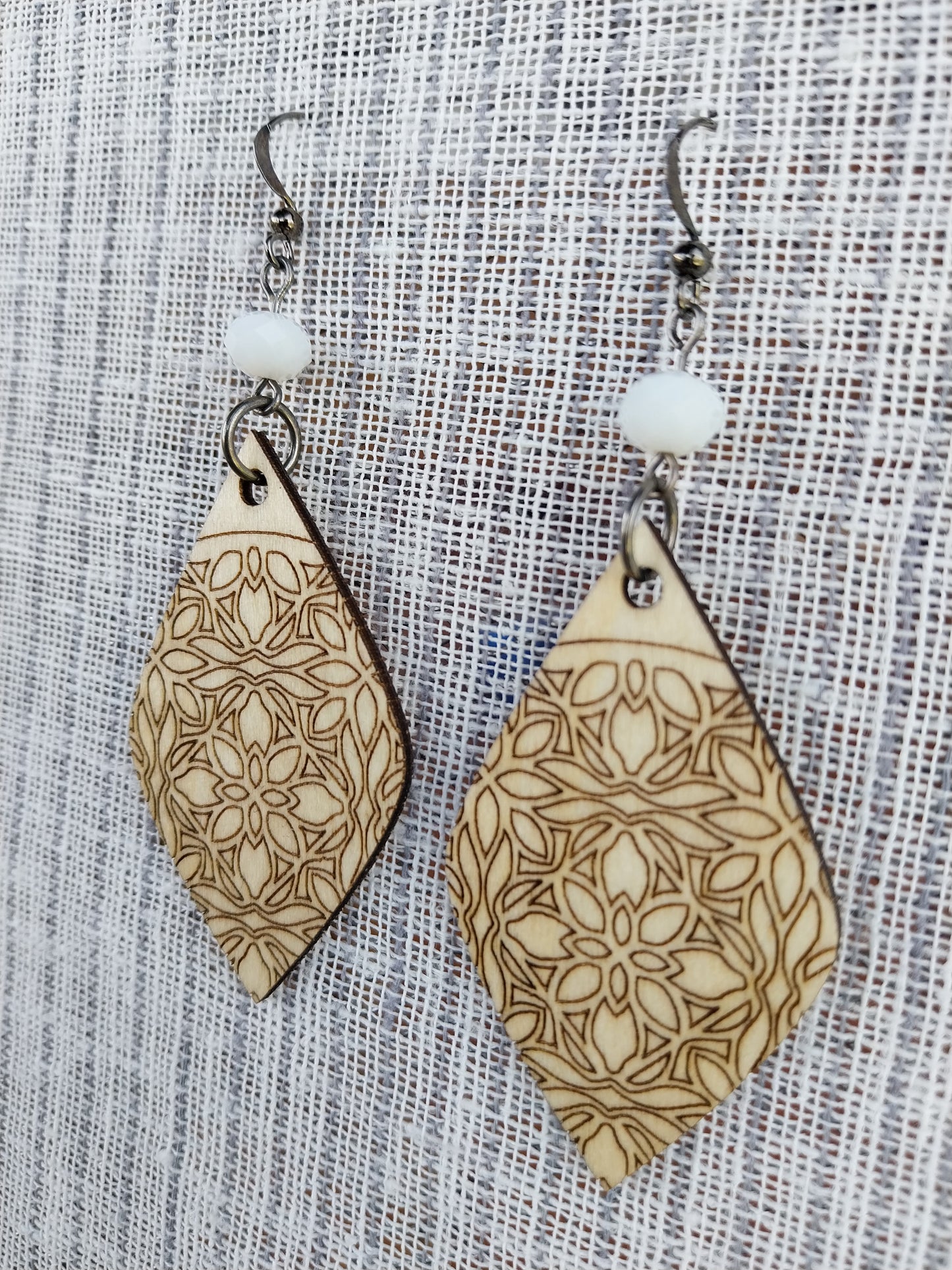 Boucles d'oreille dentelle de bois gravé et perles à facettes blanc laiteux.